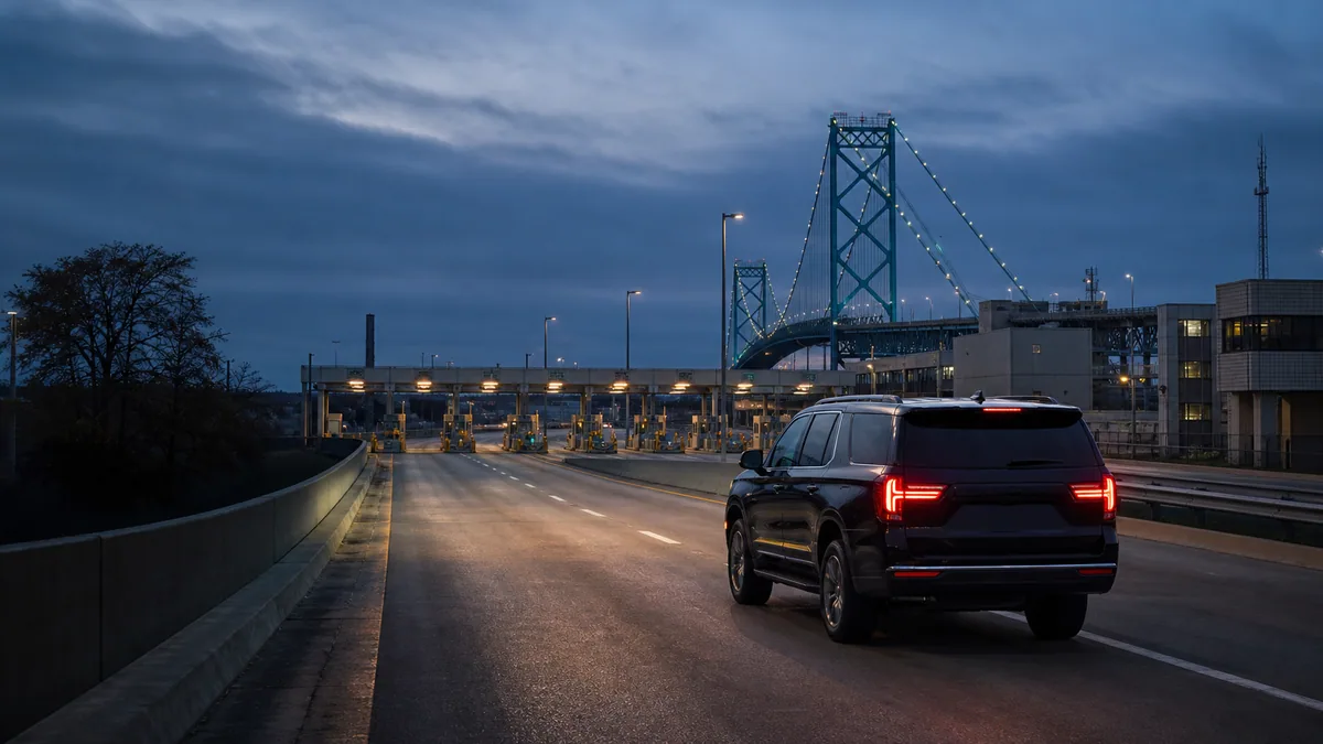 Black executive SUV approaching the Ambassador Bridge border crossing at blue hour